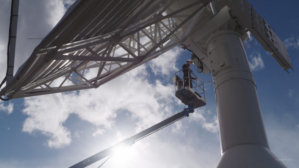 En person i en skylift gör underhållsarbete på en antenn hos forskningsanläggningen Esrange. Foto: SCC.